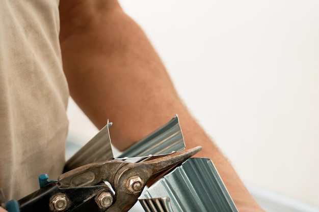 Free photo worker cuts steel profiles for drywall, close-up, selective focus. preparing for the installation of the ceiling profile system frame. renovation and repair