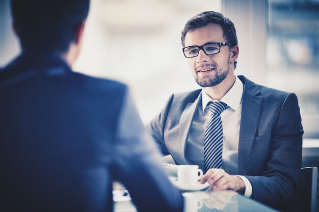 Worker drinking a cup of coffee with a colleague