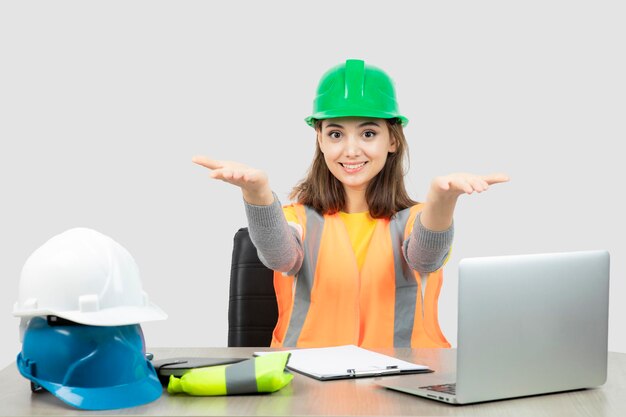 Worker female in uniform sitting at the desk and showing opened palms . High quality photo