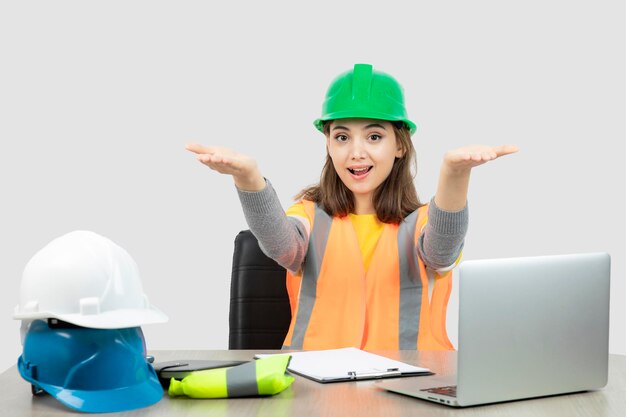 Worker female in uniform sitting at the desk and showing opened palms . High quality photo