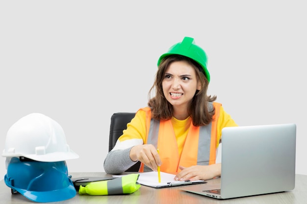 Worker female in uniform sitting at the desk with laptop and clipboard . High quality photo