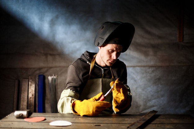 Worker holding plasma equipment in steel factory.