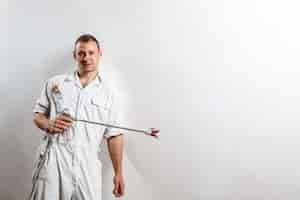 Free photo worker holding spray gun on white wall.