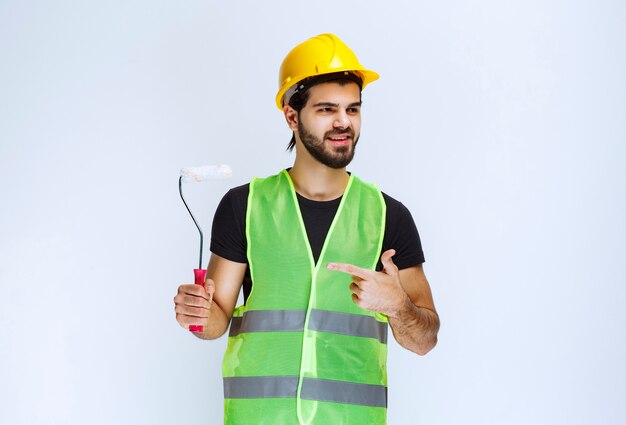 Worker holding a white trim roller for wall painting .