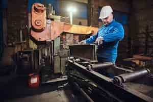 Бесплатное фото Рабочий контролирует процесс резки рельсов на оживленном металлургическом заводе.