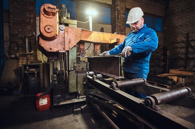 Worker is controlling a process of rail cutting at busy metal factory.