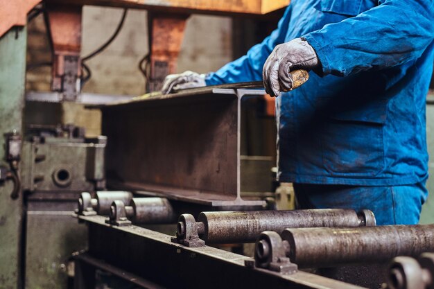 Worker is controlling a process of rail cutting at busy metal factory.