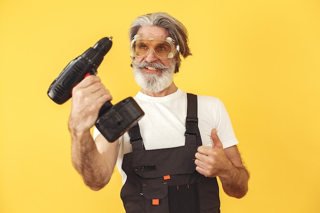 Worker in overalls. Man with tools. Senior with screwdriver.