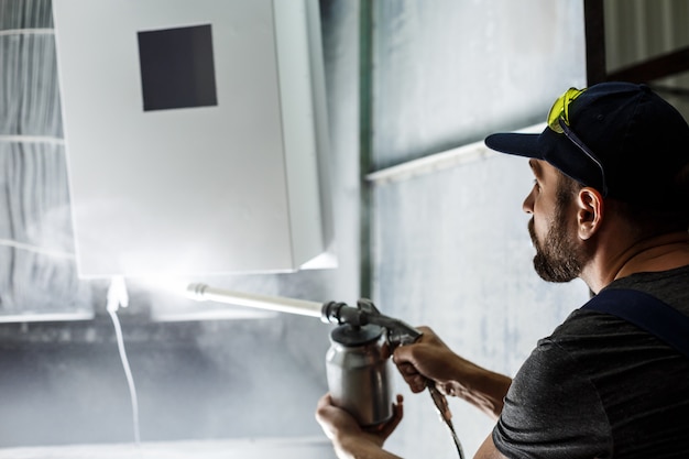 Worker painting detail with air spray pistol.