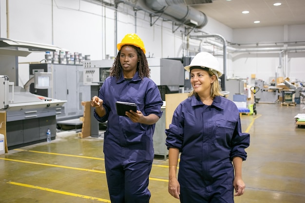 Worker pointing and talking with colleague and holding tablet