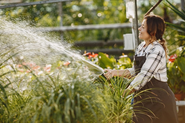 Worker pours flowerpoots. Girl in a black apron