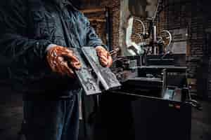 Free photo worker in protective gloves is holding freshly cut piece of metal.