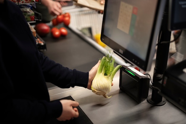 Работник сканирует овощи в супермаркете