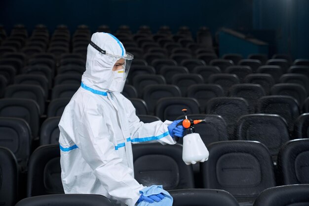 ぼろきれで映画館のホールを掃除する特別なスーツの労働者