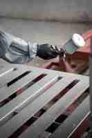Бесплатное фото Рабочий распыляет порошковую краску из пистолета сбоку