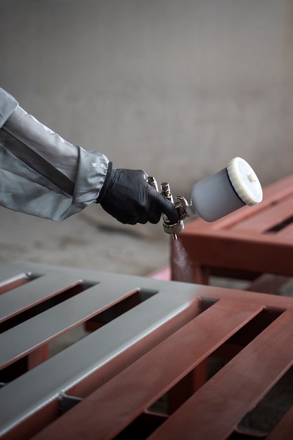 Worker spraying powder paint from a gun side view