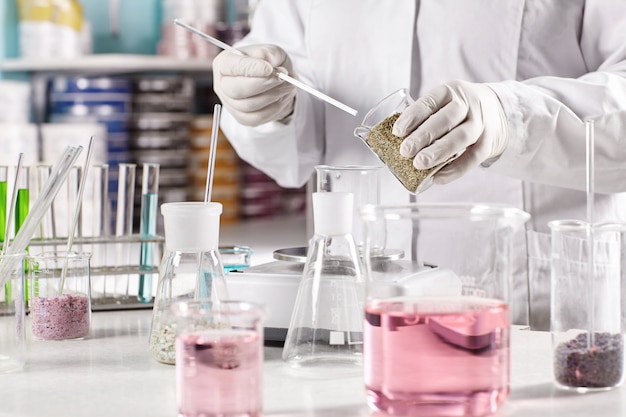 Worker surrounded with glass beakers filled with colorful liquid