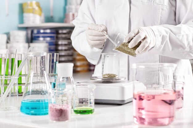 Worker surrounded with glass beakers filled with colorful liquid