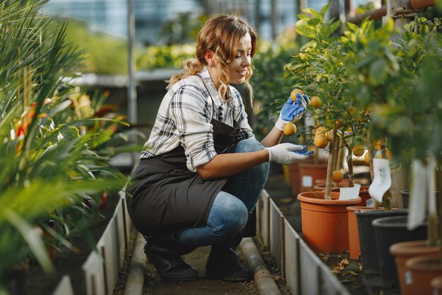 Worker take care to flowerpoots. Girl in a white shirt. Woman in a gloves