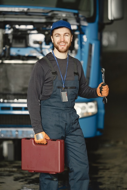 Worker in uniform. Man repairs a truck. Man with tools