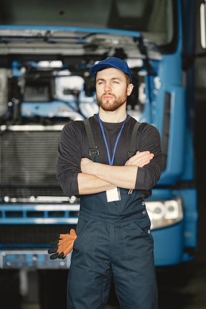 Foto gratuita operaio in uniforme. l'uomo ripara un camion. uomo con strumenti