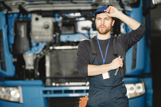 Operaio in uniforme. l'uomo ripara un camion. uomo con strumenti