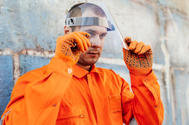 Worker in uniform with face shield and protective gloves