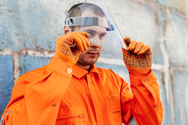 Worker in uniform with face shield and protective gloves