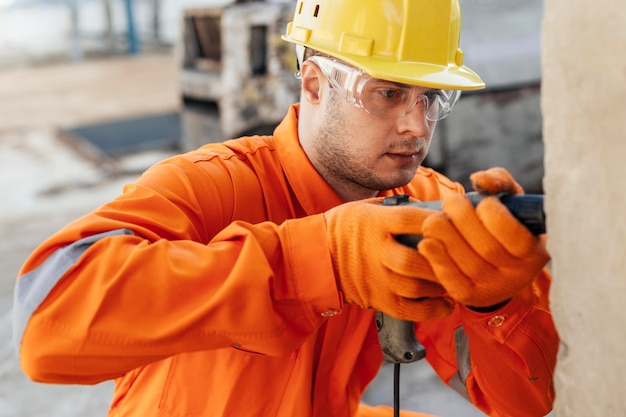 Foto gratuita operaio in uniforme con elmetto e trapano