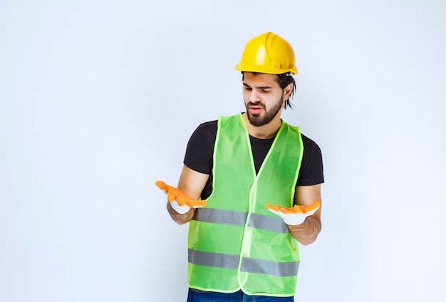 黄色いヘルメットと作業場の手袋を着用している労働者。