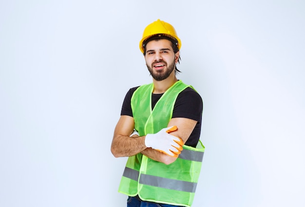 Worker wearing yellow helmet and workshop gloves .