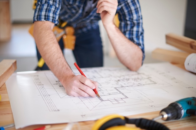 Worker with Amendments on blueprint of house