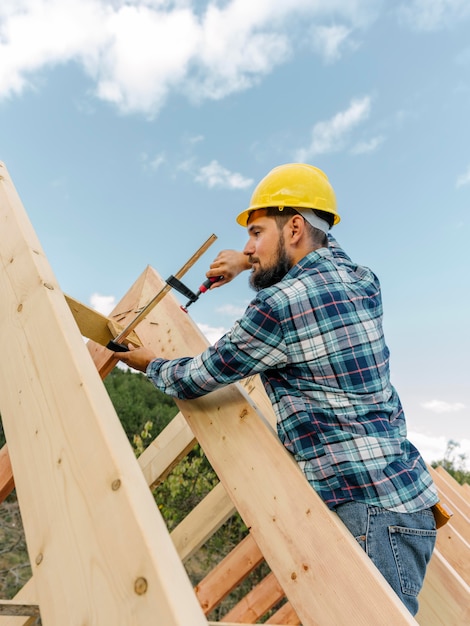 Worker with hard hat building the roof of the house