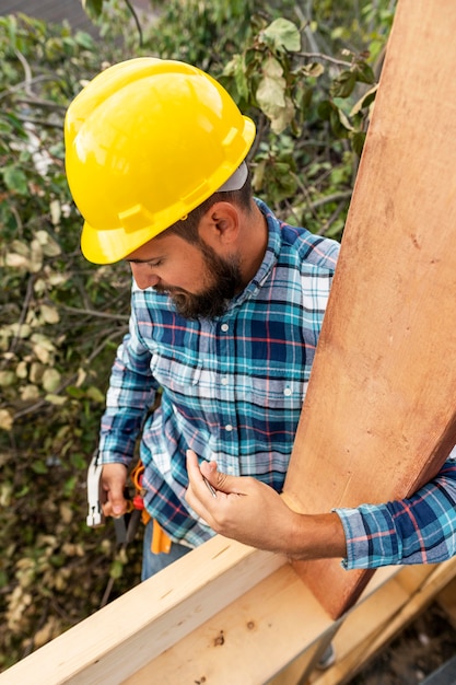 Worker with hard hat building with wood