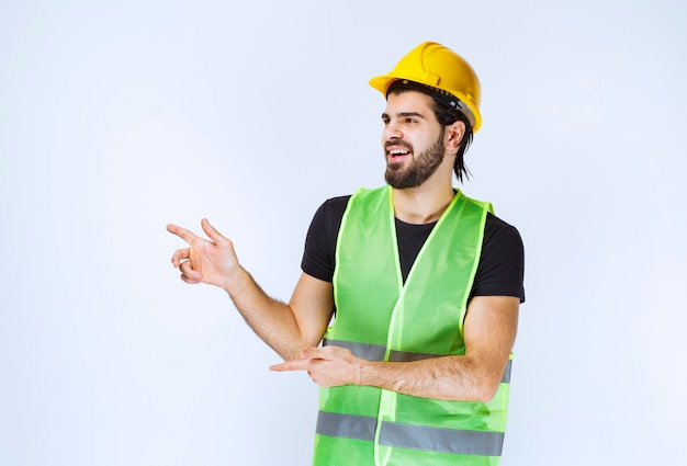 Worker in yellow helmet showing left side.