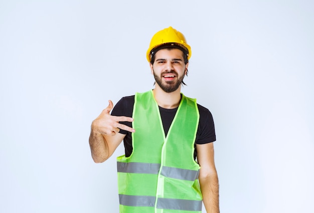 Worker in yellow helmet showing peace sign.