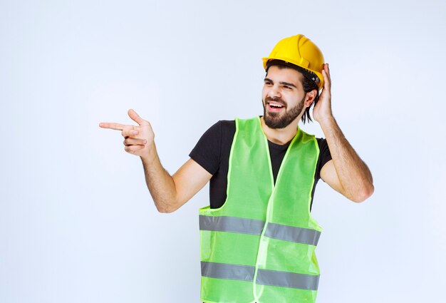 Worker in yellow helmet thinking and looks confused.