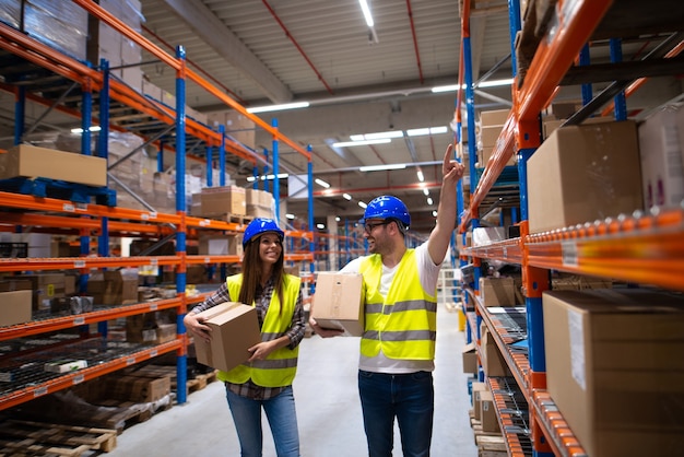 Workers carrying boxes and relocating items in large warehouse center