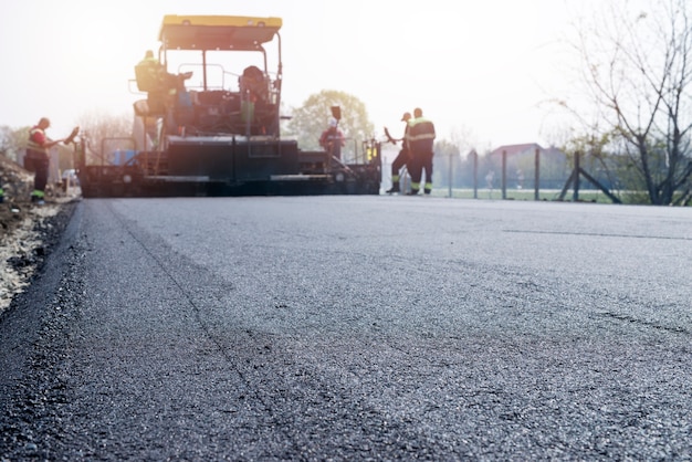 Workers placing new coating of asphalt on the road