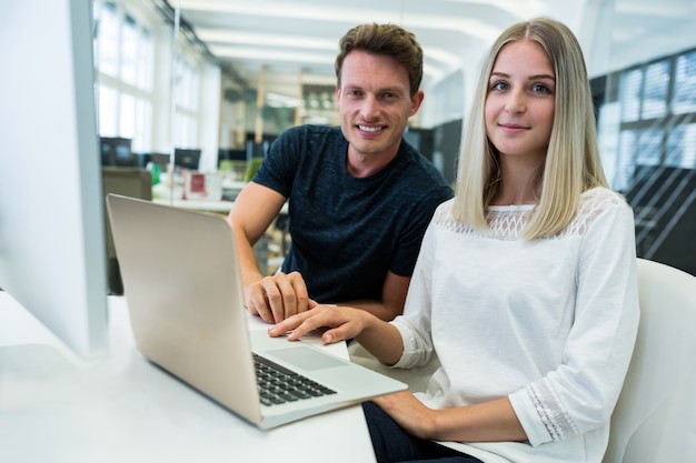 Workers smiling in front of a laptop