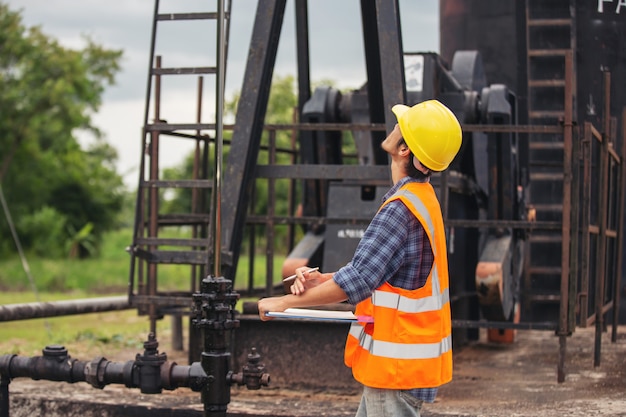 Workers standing and checking beside working oil pumps.