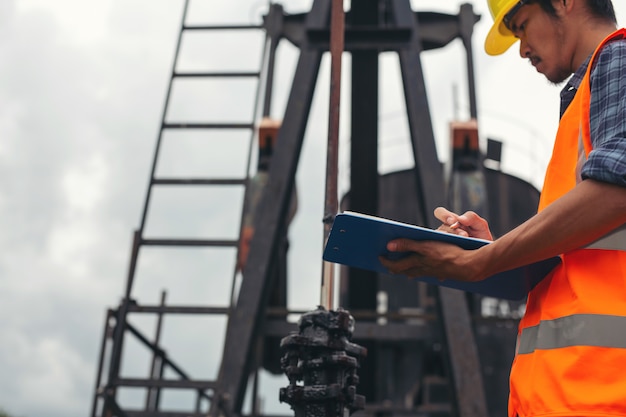 Free photo workers standing and checking beside working oil pumps.