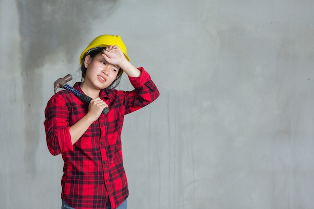 Free photo workers woman tired and holding hammer in construction site