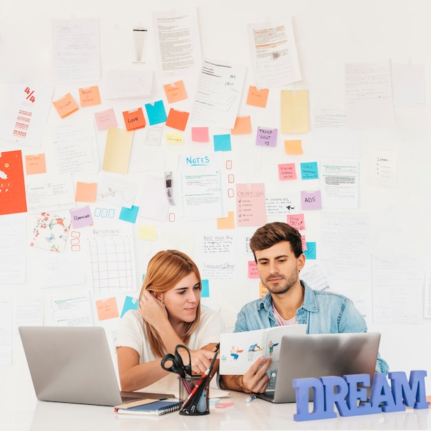 Working colleagues looking at paper at workplace with laptops stationery and nameplate