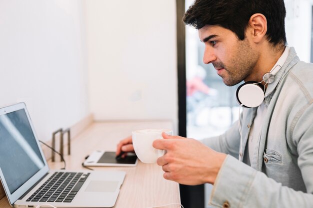 Working on laptop male drinking coffee