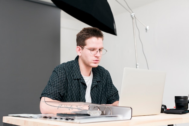 Free photo working photographer man sitting and looking at his laptop