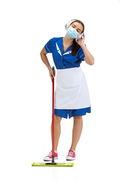 Working with music. Portrait of female made, housemaid, cleaning worker in white and blue uniform isolated on white 