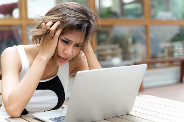 働く女性は深刻な感じとテーブルの上のノートパソコン