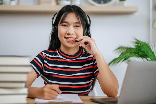 テーブルの上で本を読んで、ヘッドフォンを身に着けている働く女性