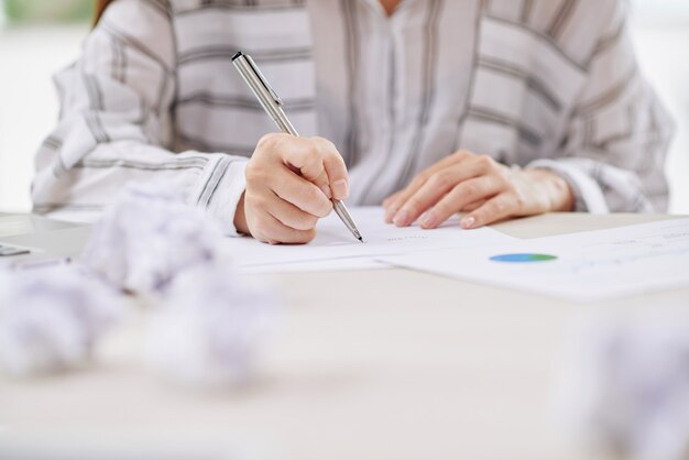 Работающая женщина пишет на бумаге